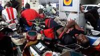 A taxi motorcyclist queuing for fuel sleeps on his bike at a Lagos filling station in Nigeria