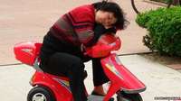 A woman sleeps on a child's scooter